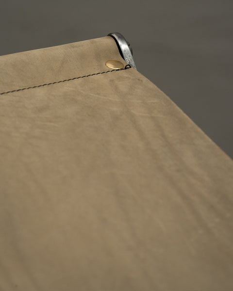 Close-up of a beige fabric with a button and stitching detail against a gray background