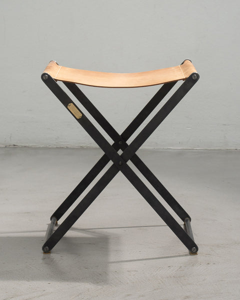 Foldable stool with leather seat on a gray background