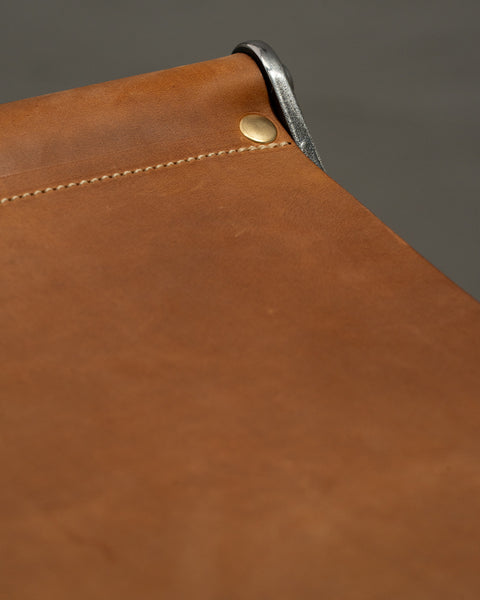Close-up of a brown leather surface with stitching detail on a gray background